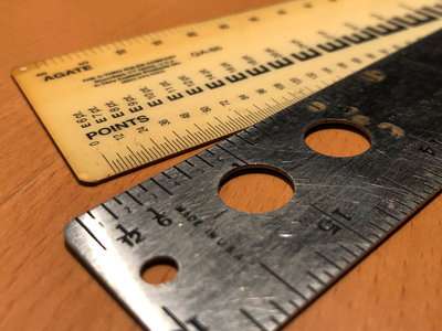 A close-up of two point-and-pica rulers
